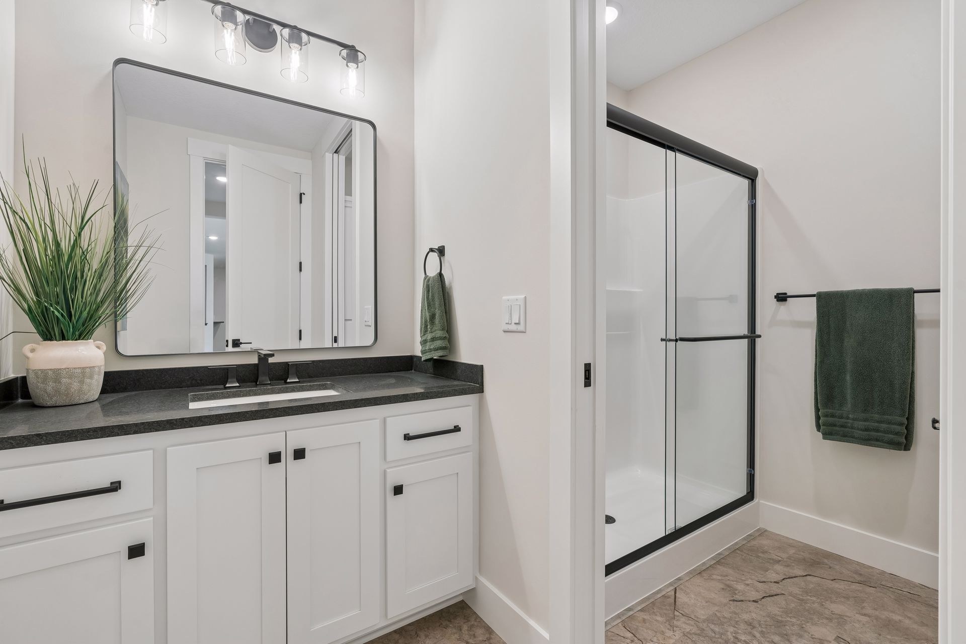 Lower level bathroom with white vanity, black fixtures and walk-in shower